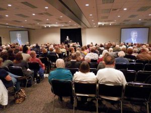 Photo of a conference room with rows of people.