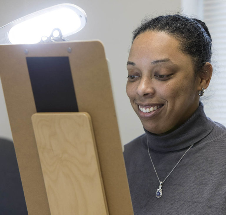 A woman looks at a clipboard with a bright light shining on it