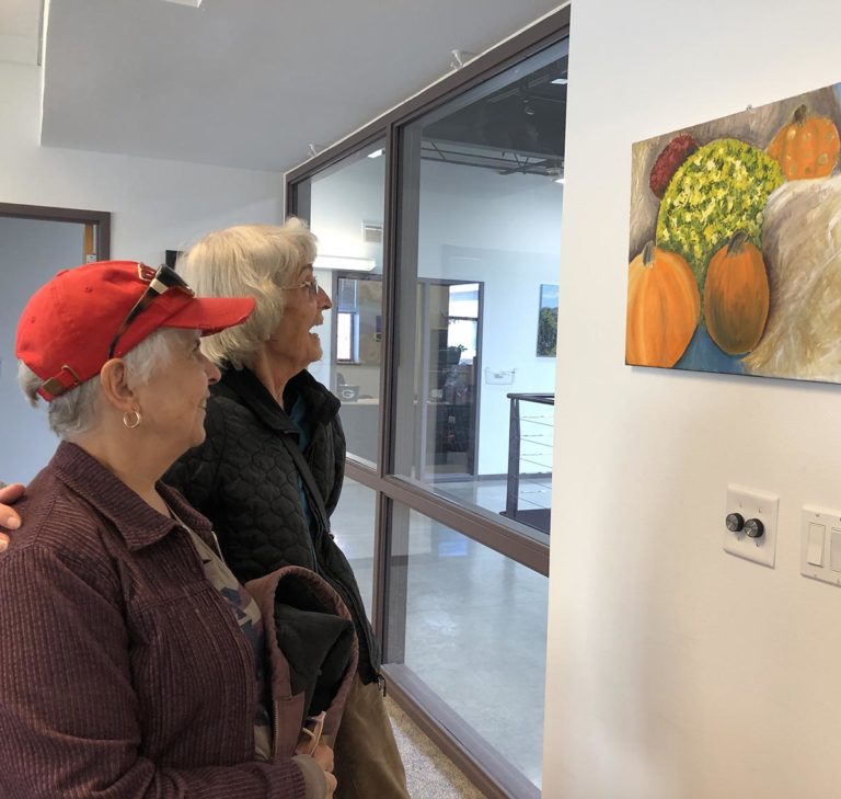 Two older women look at a painting at Gallery Night