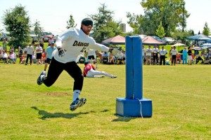 A man wearing a blindfold runs at a large foam cylinder.
