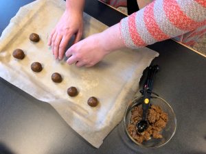 Hand-rolled cookie dough balls are placed on a baking sheet lined with parchment.