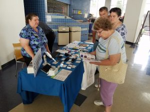 Heather Buggs at Wisconsin Council of the Blind Table at fair with people asking questions