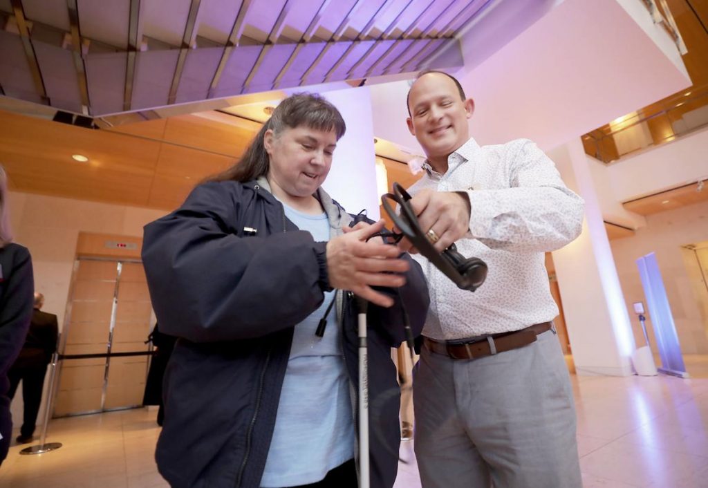 A man hands a headset to a woman.