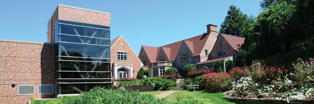A large brick building surrounded by gardens.