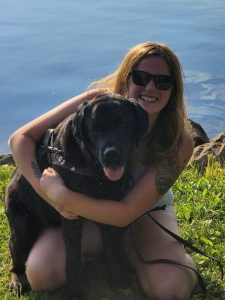 Shannon Columb hugs a black lab.