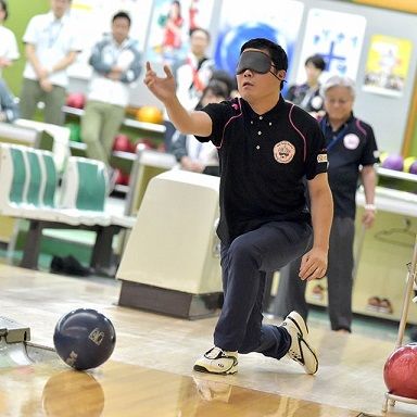 A man bowls while wearing a blindfold.