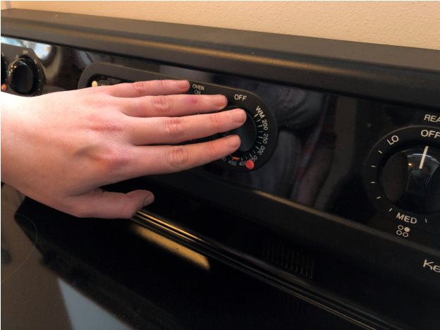 A hand touches a microwave button that is covered with an orange bump dot.