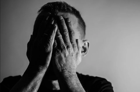 A man holds his hands up over his face