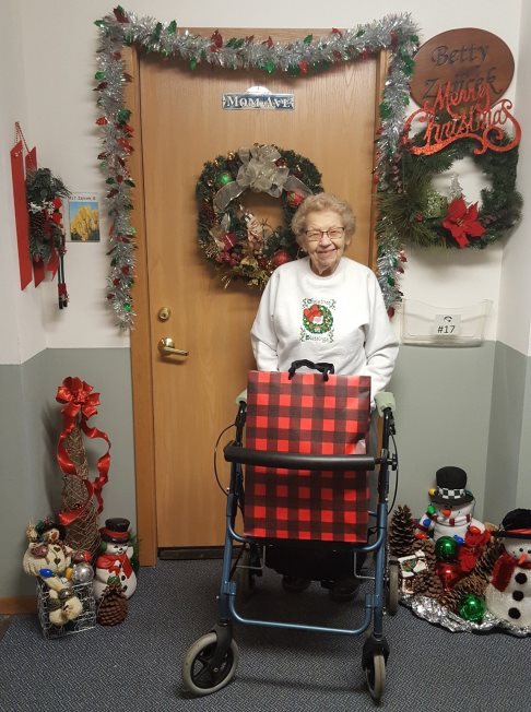 A woman stands with a walker surrounded by Christmas decorations. 