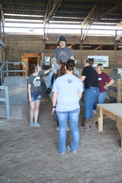 Four people stand around a man on a horse.