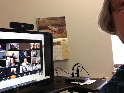 A computer with 16 squares of students and part of a woman’s head.