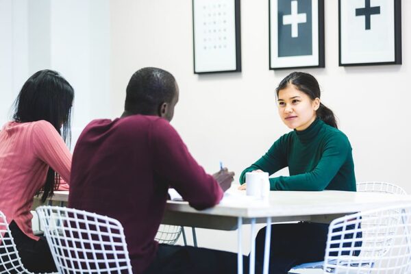 Two people interview another at a table.