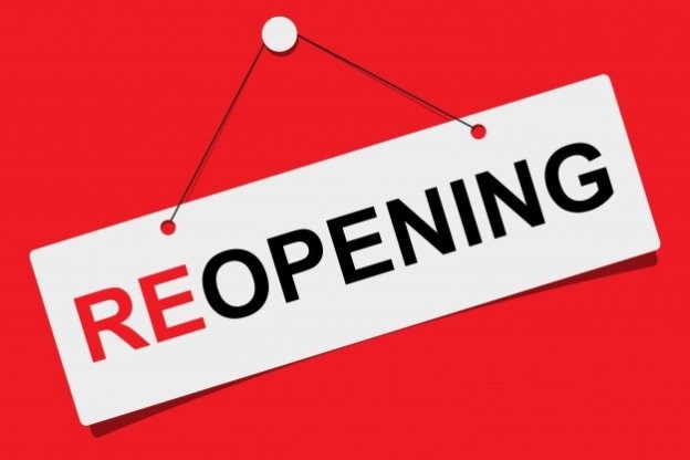 A white sign on a red background that says, “reopening” in red and black text.