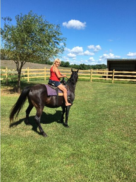 A woman on a horse outside.