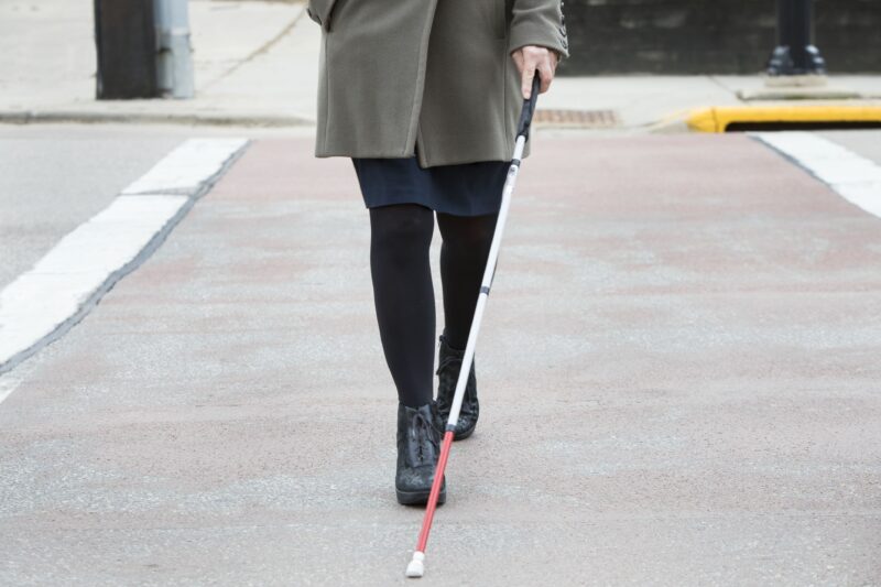 woman crossing street with cane