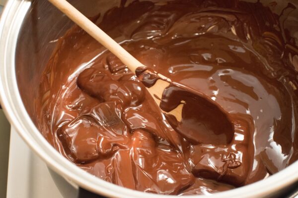 Spoon stirring melted chocolate in pan