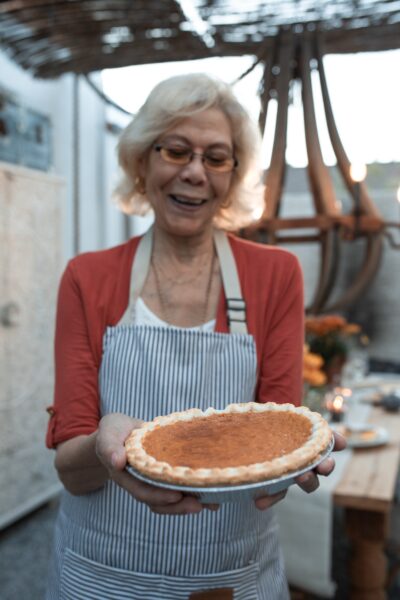 Woman in Red Cardigan Holding Brown Round Cake