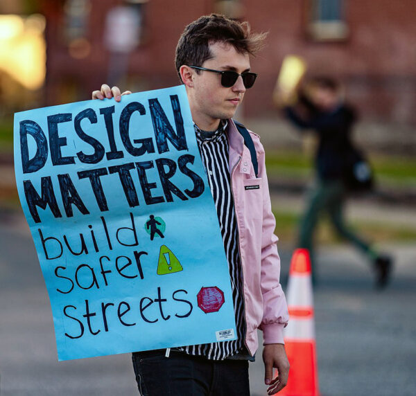 Person holding sign that says "design matters, build safer streets."