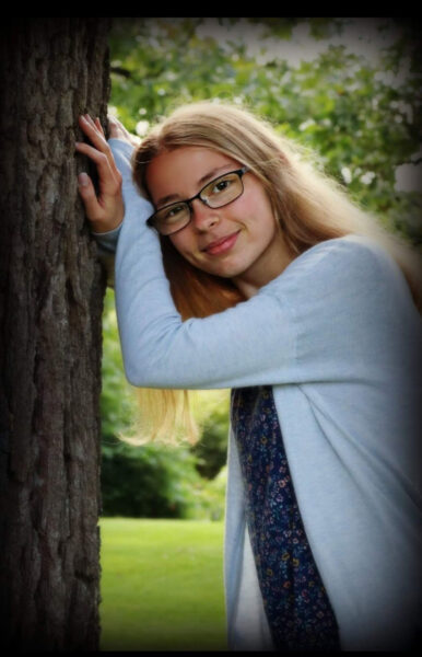 Girl leans on tree