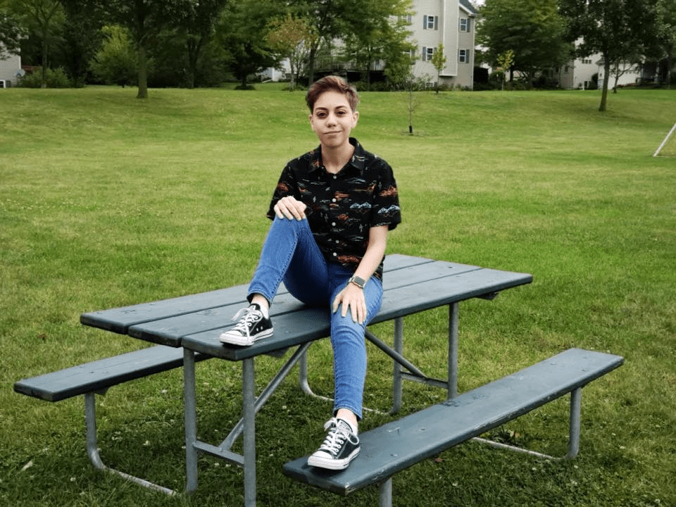 Luka Santin sitting on a picnic bench in a field.