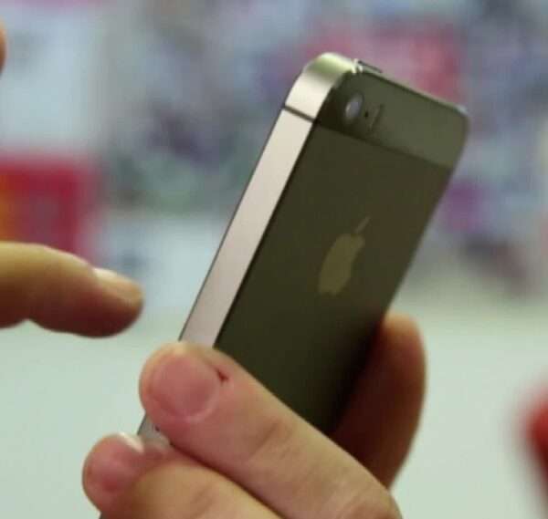 Fingers of one hand holding an iPhone with a finger of another hand preparing to dial.