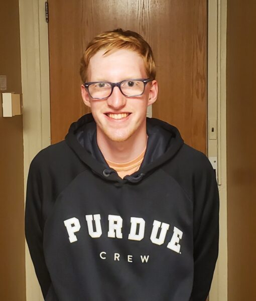 A young man wearing glasses and a hoodie that says Purdue Crew.