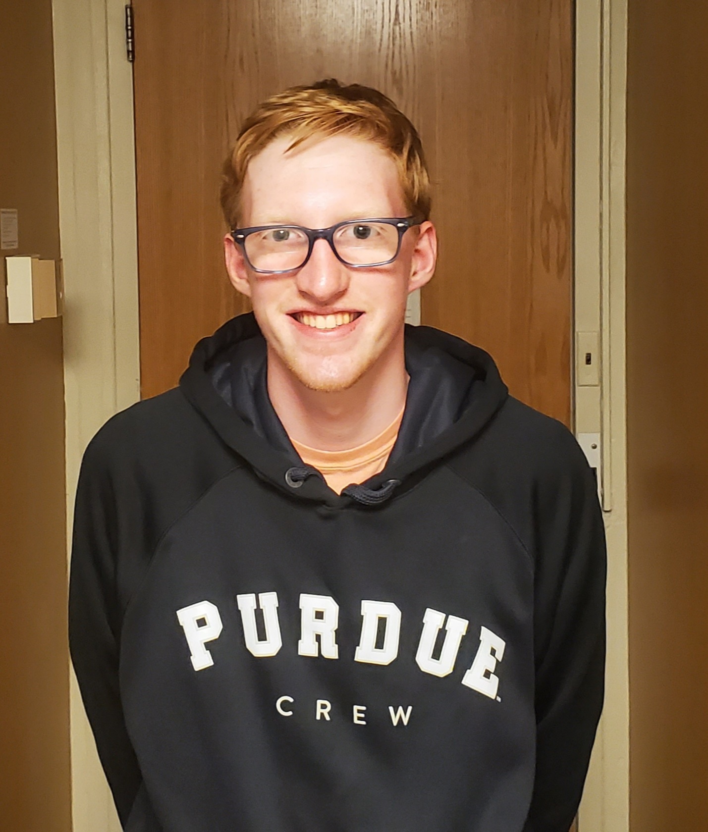 A young man wearing glasses and a hoodie that says Purdue Crew.