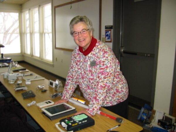 A woman standing at a table on which several adaptive products are displayed.