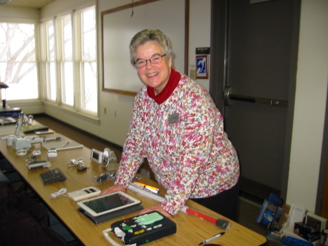 A woman standing at a table on which several adaptive products are displayed.