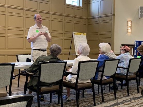 Jim Denham standing in front of a table at which several women are seated