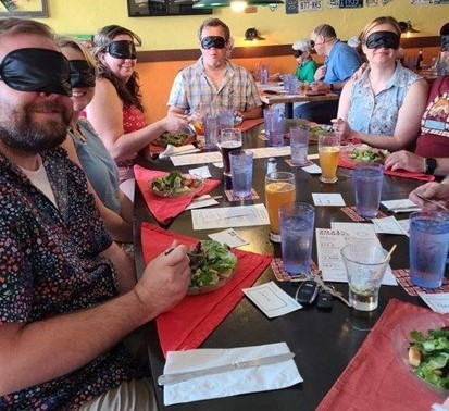 A table of blindfolded diners eating salads at Beastro & Barley