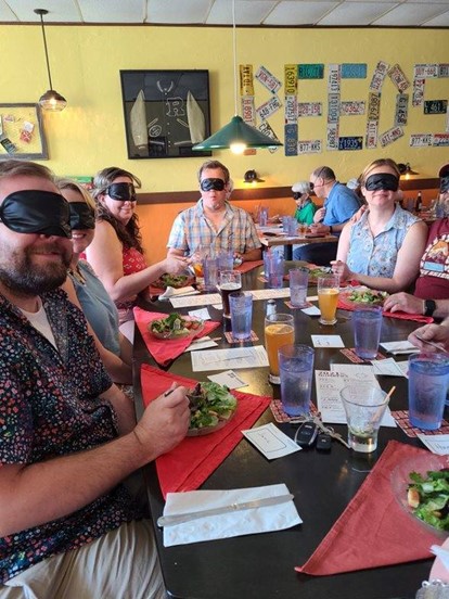 A table of blindfolded diners eating salads at Beastro & Barley