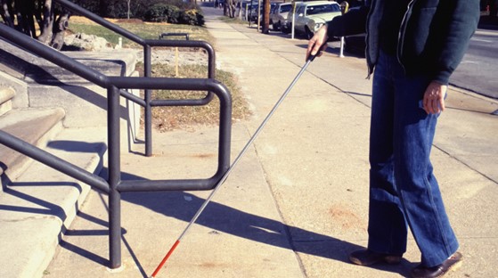 A person using a white cane approaching stairs