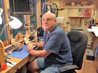Don McCall sitting at a workbench in a woodcarving workshop