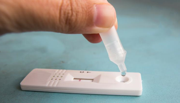 persons hand using an at home covid test