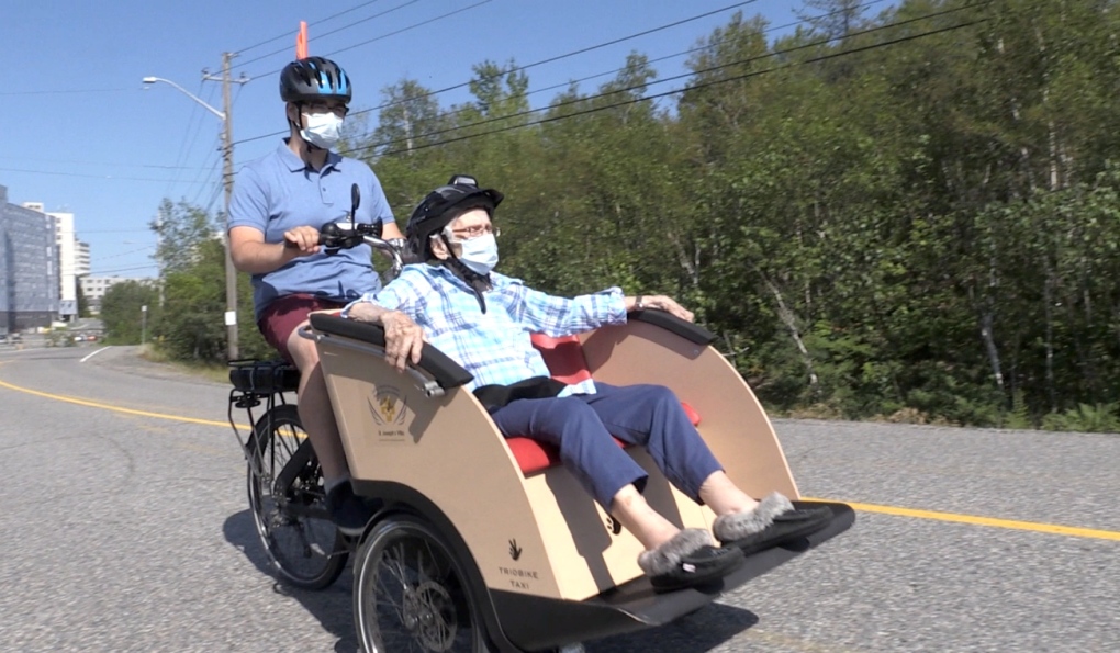 A man riding in a trishaw pedaled by another man
