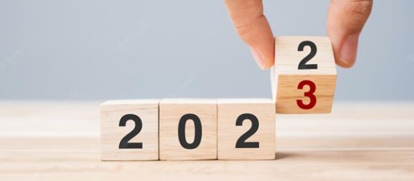 Blocks spelling out the year 2022 with fingers turning the last digit to 3