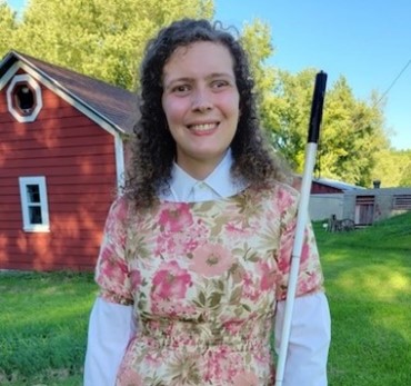 Chamomile Harrison standing in a yard with a barn or garage in the background