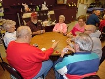 A group of people playing a card game at a round table