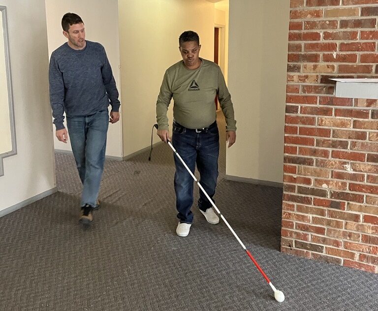 Brent works with a client using a white cane in their home
