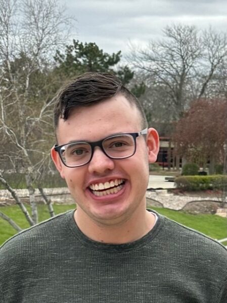 Luke Robel wearing glasses outdoors smiling for the camera