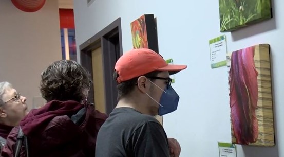 Three people looking at art hanging on a wall