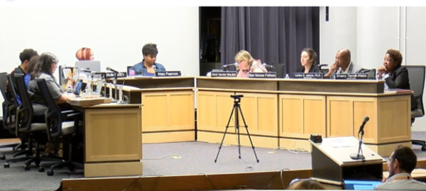 A meeting of the Madison School Board with members seated around a U-shaped table