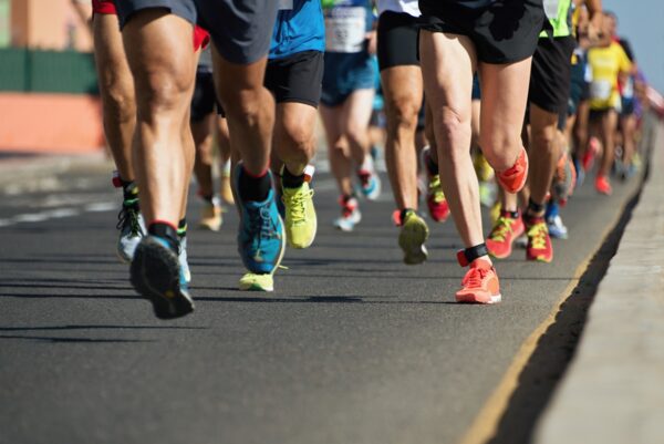 The legs of many people running on a road