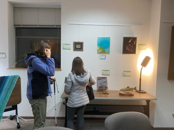 Two people exploring art displayed on a table