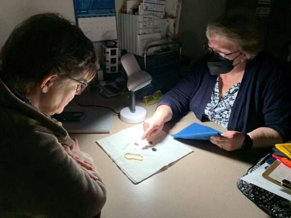 A low vision therapist showing a client how to use contrast and lighting to more easily spot small objects