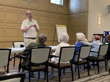 Jim Denham standing in front of a table at which several women are seated