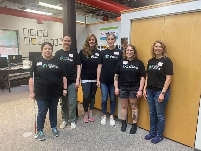 A group of six volunteers from Exact Sciences posing for the camera in the Sharper Vision Store.