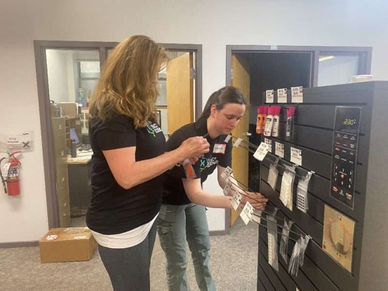 Two volunteers replacing hooks on a store display.