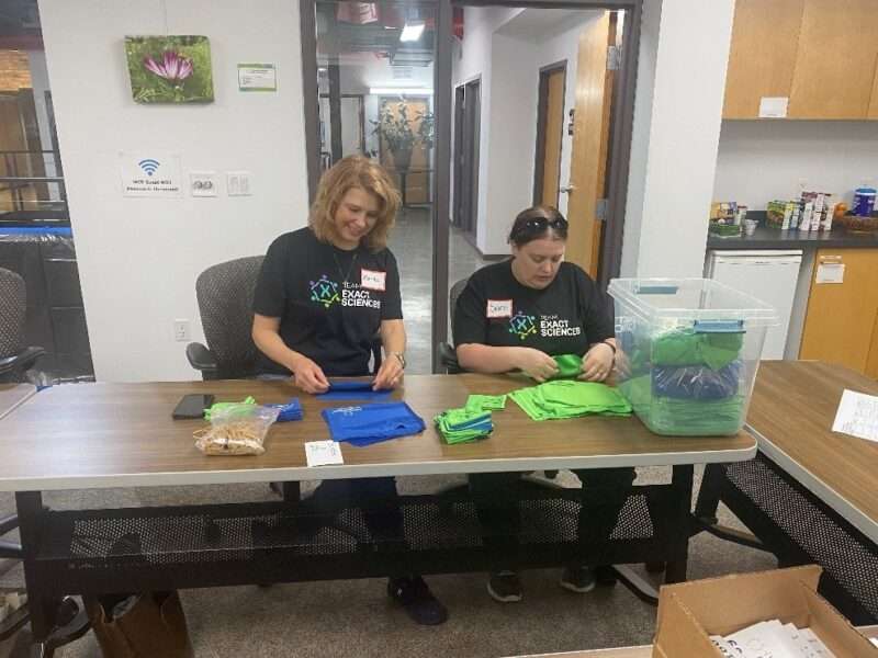 Two volunteers sitting at a table organizing lens cloths for tabling events.